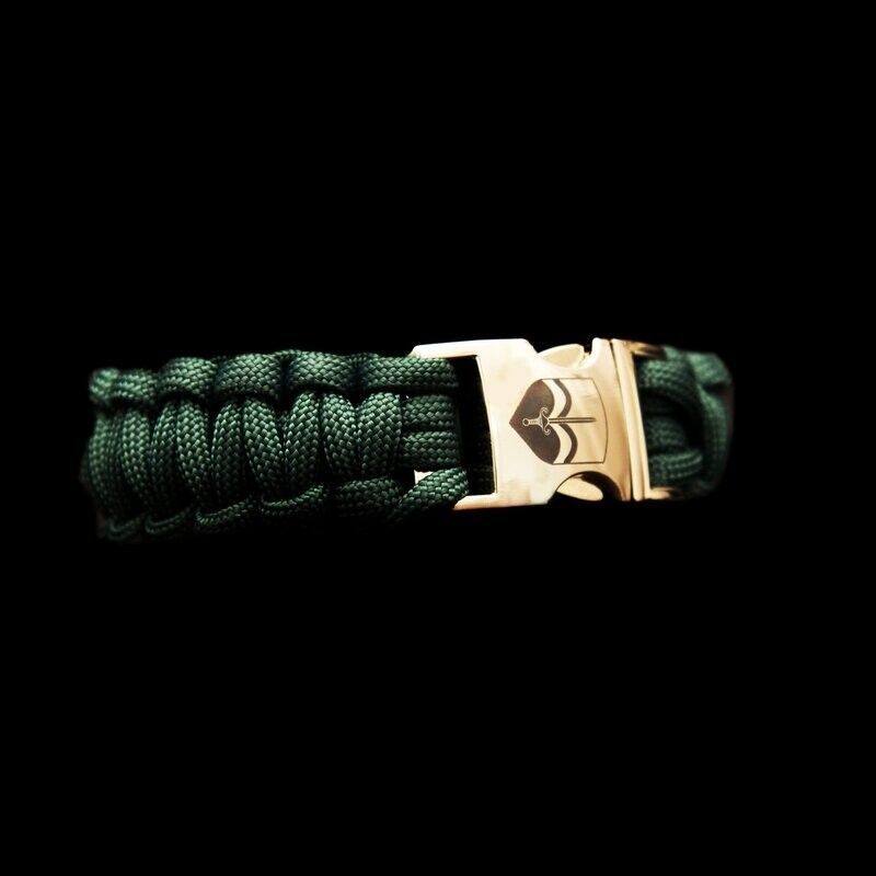 Een groene paracord armband met een gouden gesp op een zwarte achtergrond.