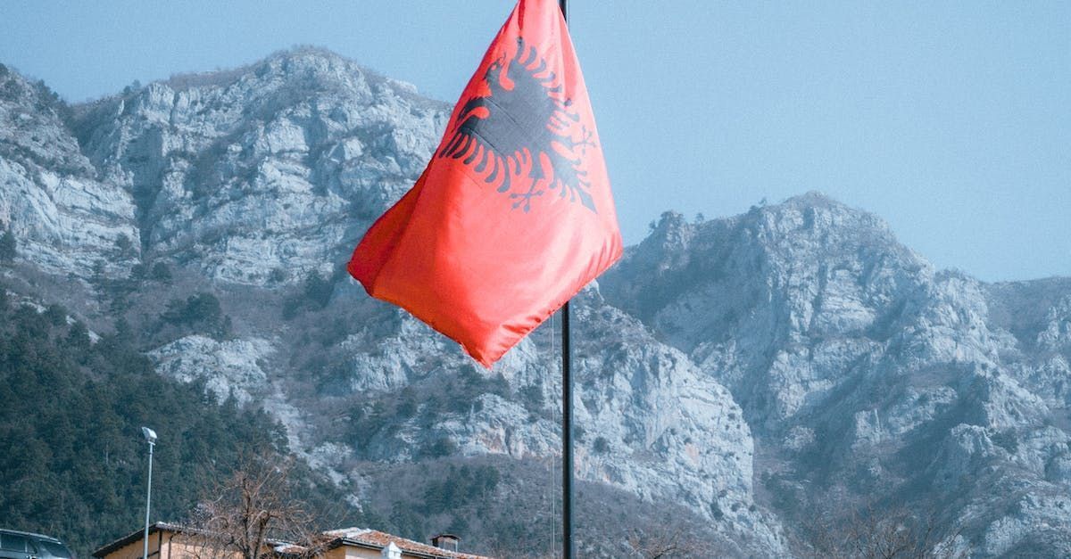 Er wappert een rode vlag voor een besneeuwde berg.