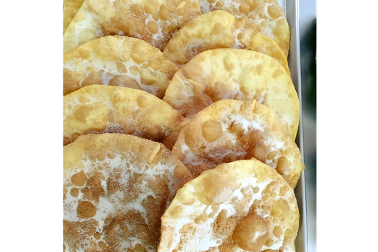 Two sandwich halves on a white plate, with bread, tomato, lettuce, and filling.