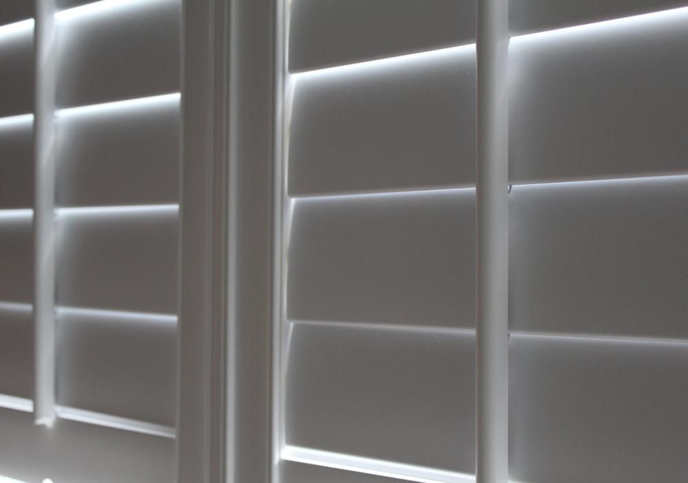 White, Partially Closed Plantation Shutters Casting Horizontal Shadows — My Timber Flooring Blinds & Shutters in Erina, NSW