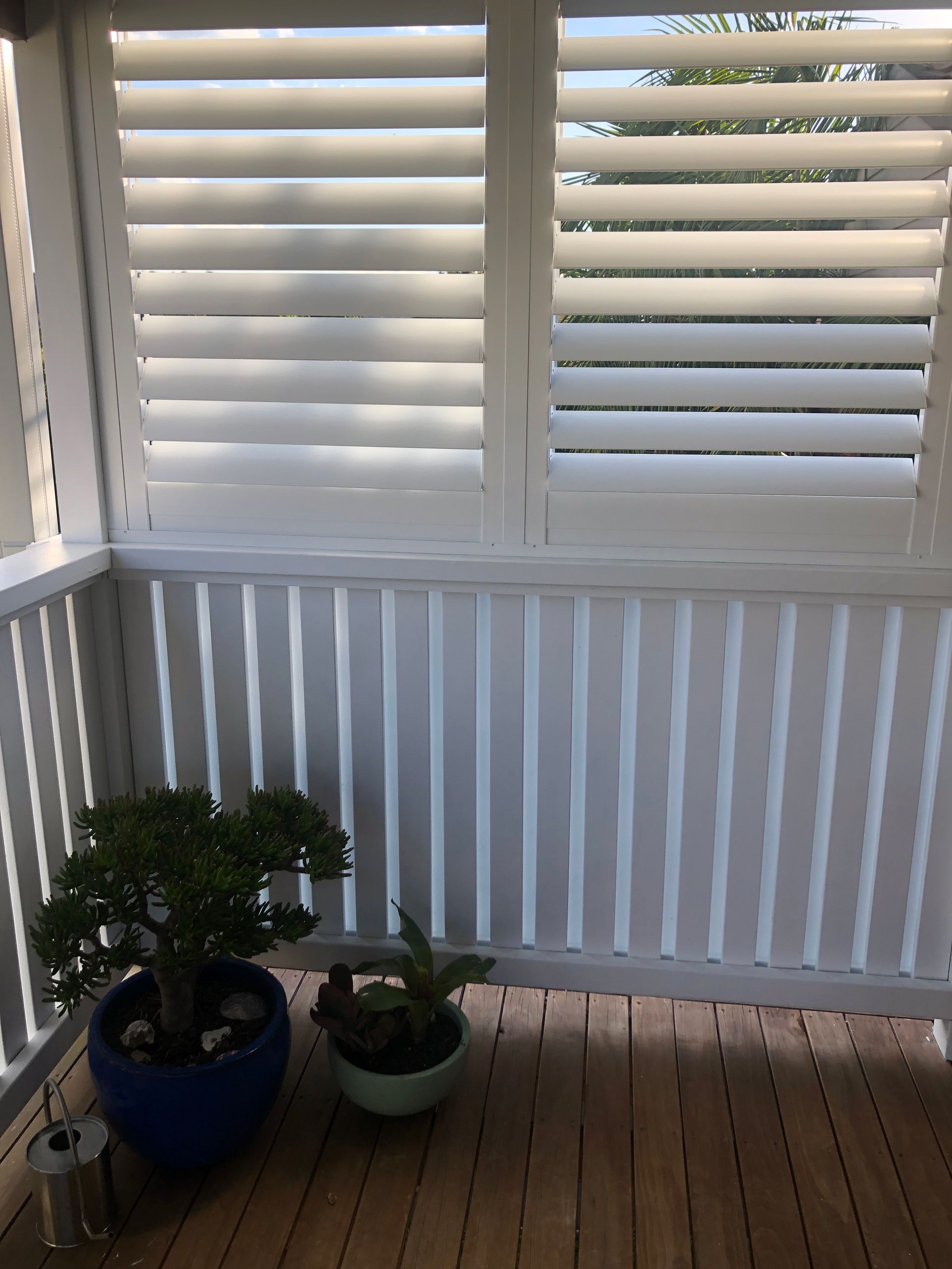 White Shuttered Windows and Railing on a Wooden Deck, With Potted Plants — My Timber Flooring Blinds & Shutters in Erina, NSW