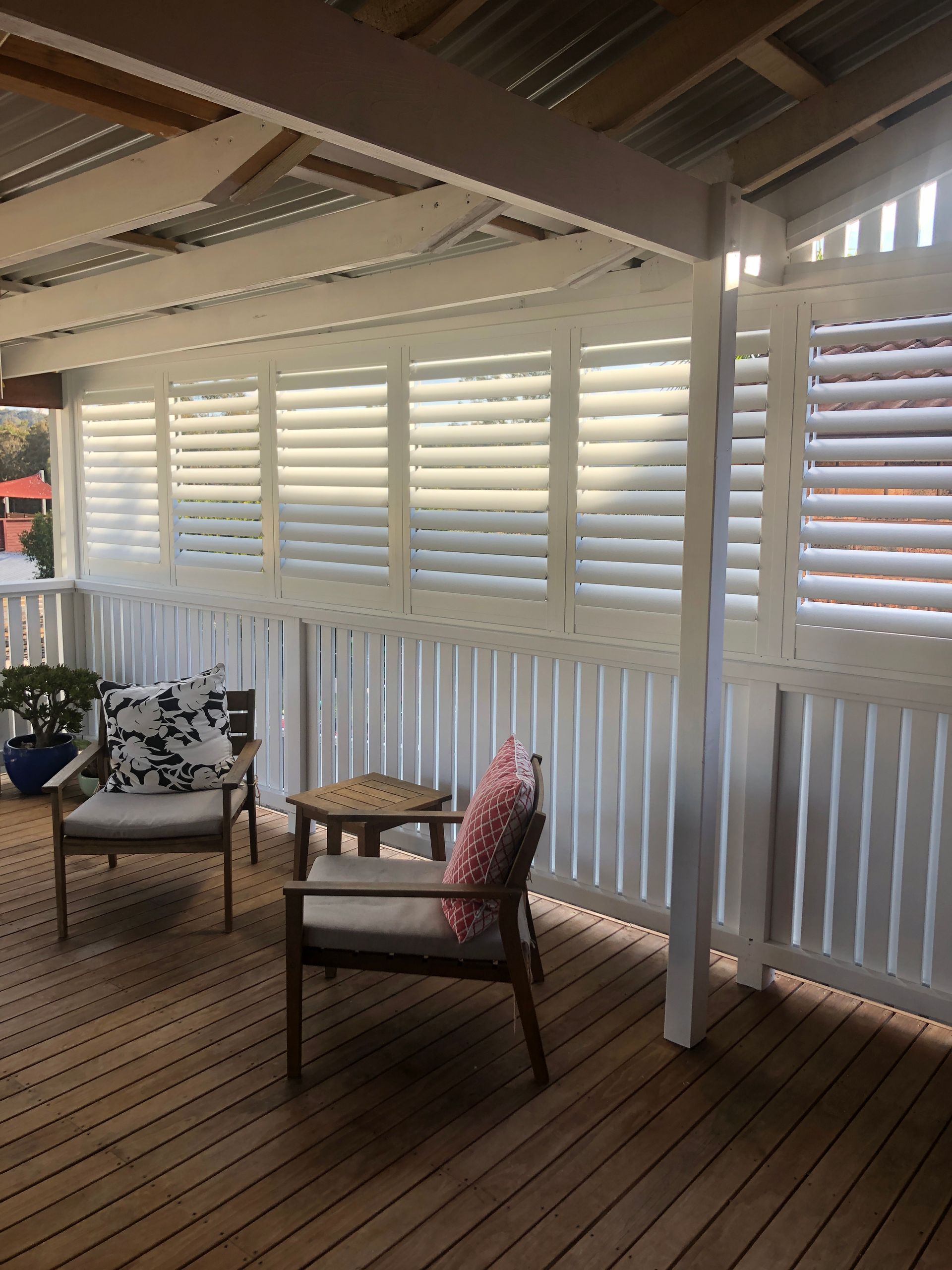 Deck With White Shutters, Two Chairs, and a Small Table. Wooden Floor and Roof — My Timber Flooring Blinds & Shutters in Erina, NSW