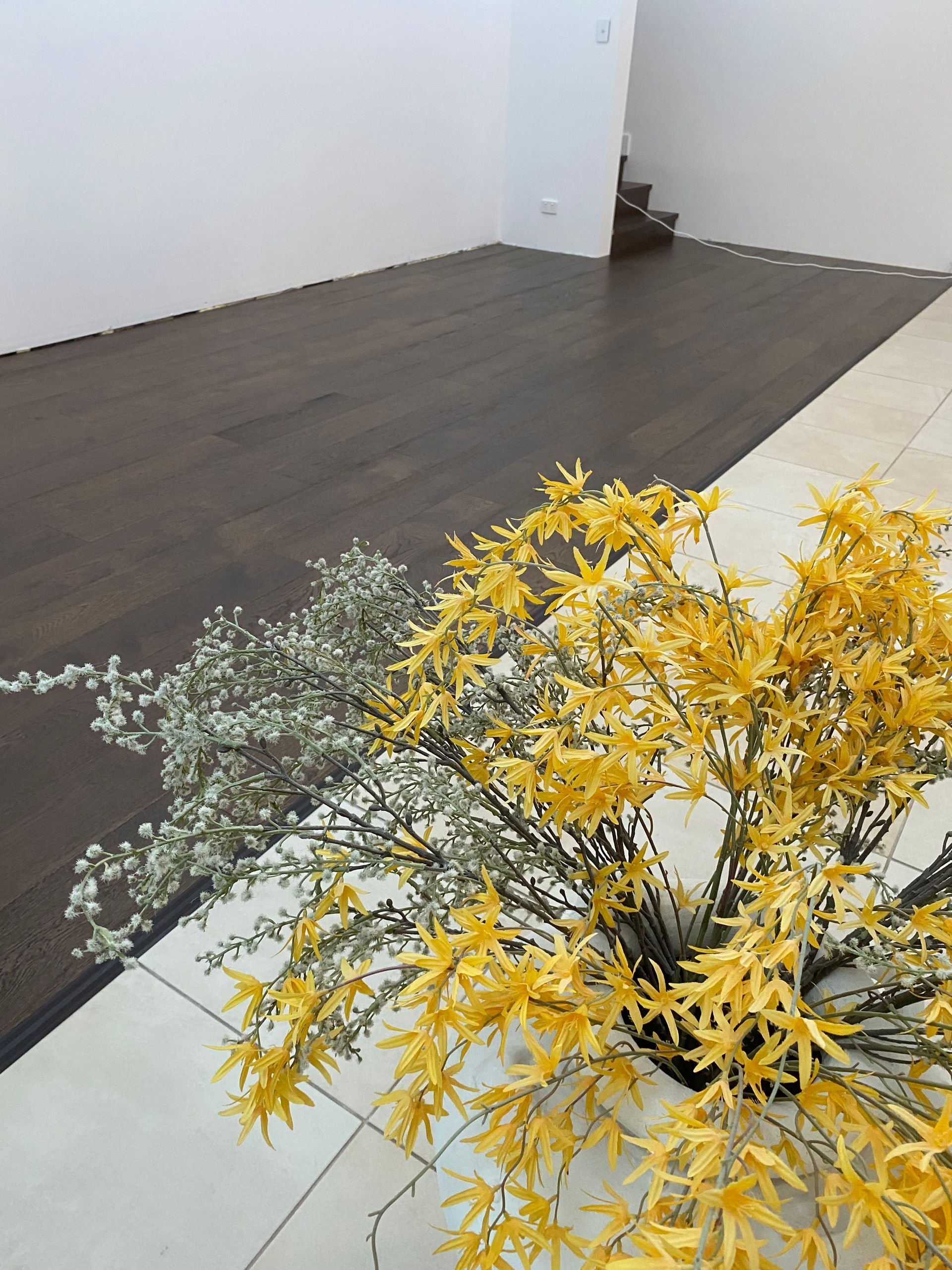 Vase of Yellow and White Flowers, Dark Wood Flooring, and White Tiles in a Room With a Stairwell — My Timber Flooring Blinds & Shutters in Erina, NSW
