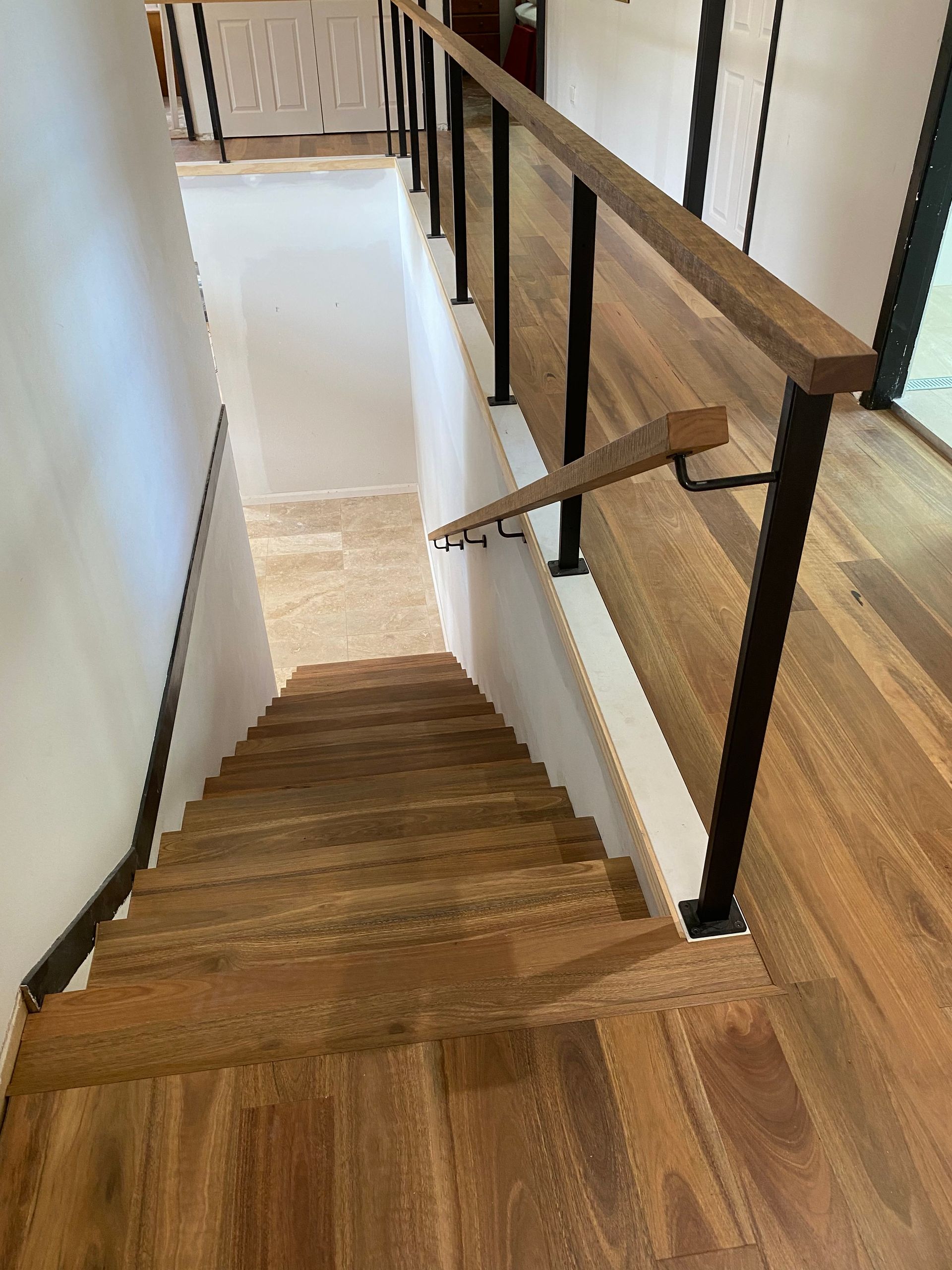 Wooden Staircase With Black Metal Railing, Descending Into a Lower Level, Natural Light — My Timber Flooring Blinds & Shutters in Erina, NSW
