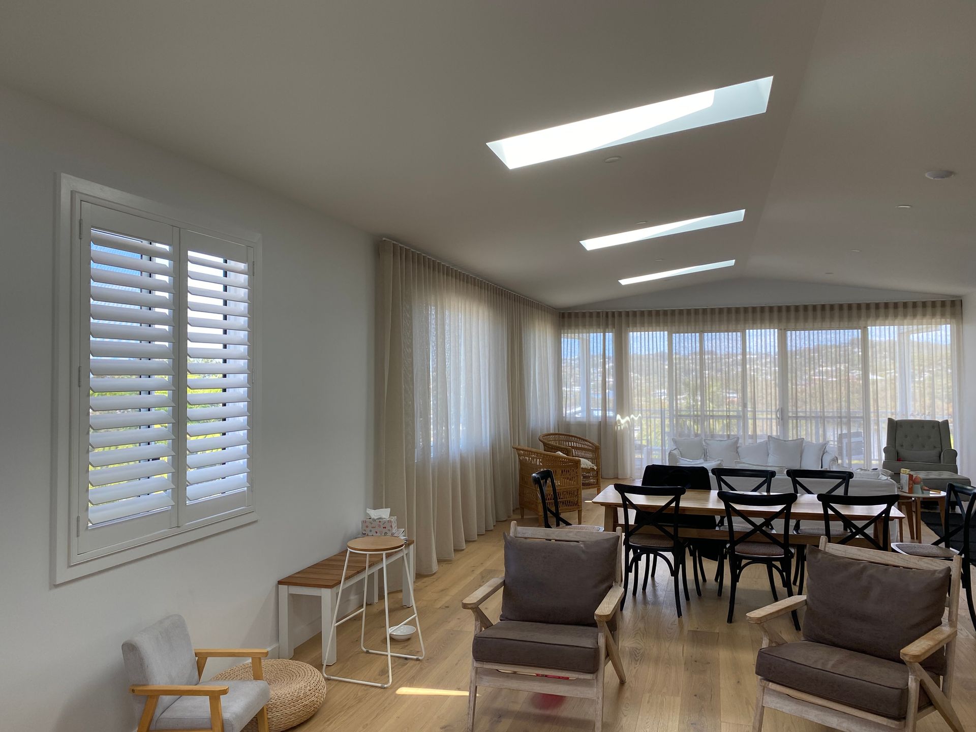 Bright Room With White Shutters, Sheer Curtains, Wood Floors, and Skylights — My Timber Flooring Blinds & Shutters in Erina, NSW