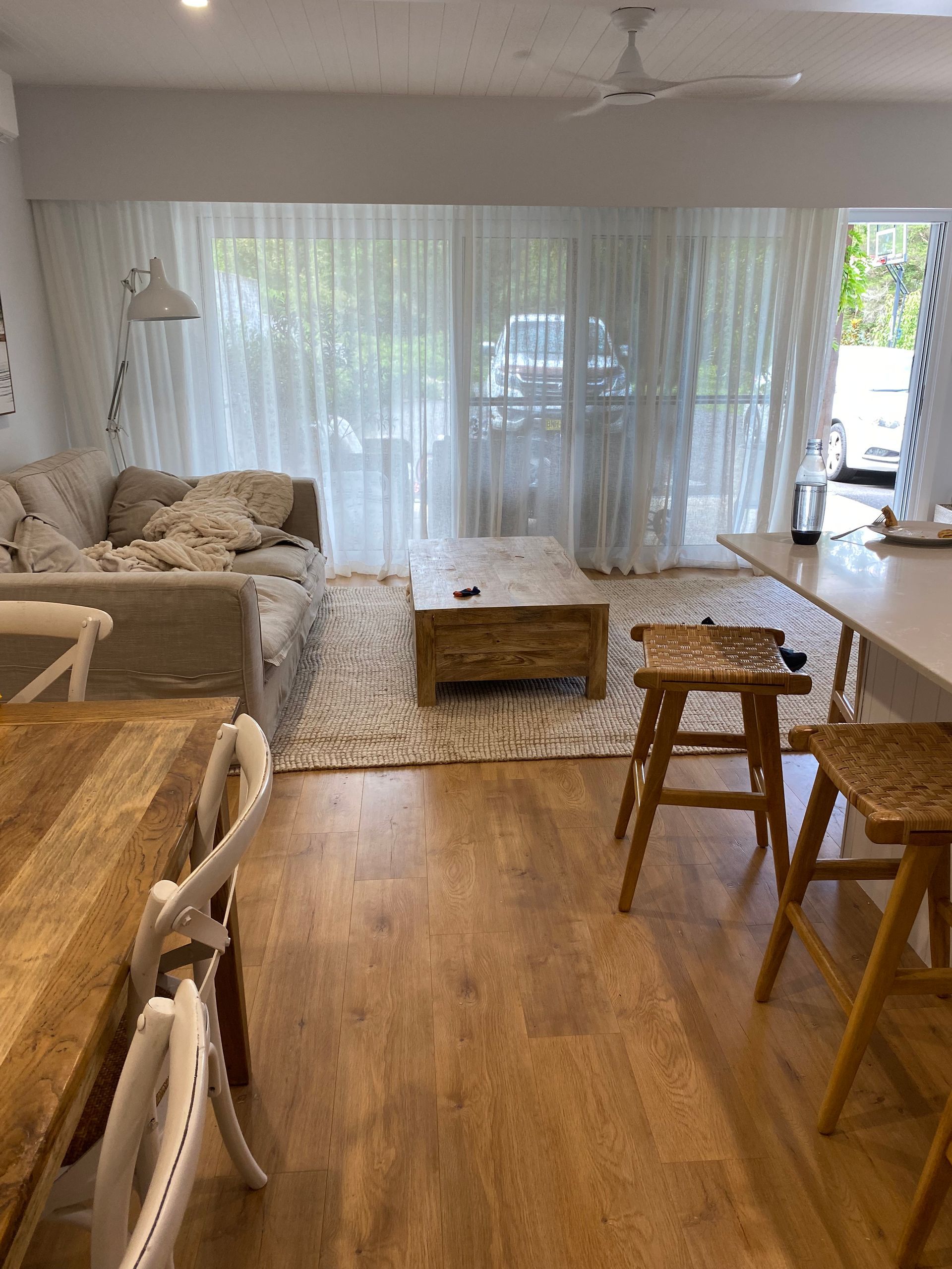 Living Room With a Couch, Coffee Table, Rug, and Dining Table; a Doorway in the Background — My Timber Flooring Blinds & Shutters in Erina, NSW