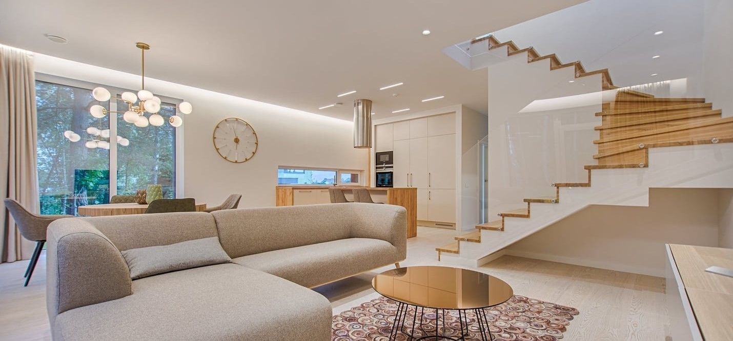 Modern Living Room With a Sectional Sofa, Wooden Stairs, and a Round Coffee Table — My Timber Flooring Blinds & Shutters in Erina, NSW
