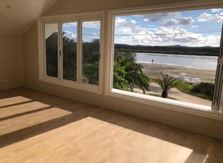 An Empty Room with Large Windows Overlooking a Beach — My Timber Flooring Blinds & Shutters in Erina, NSW