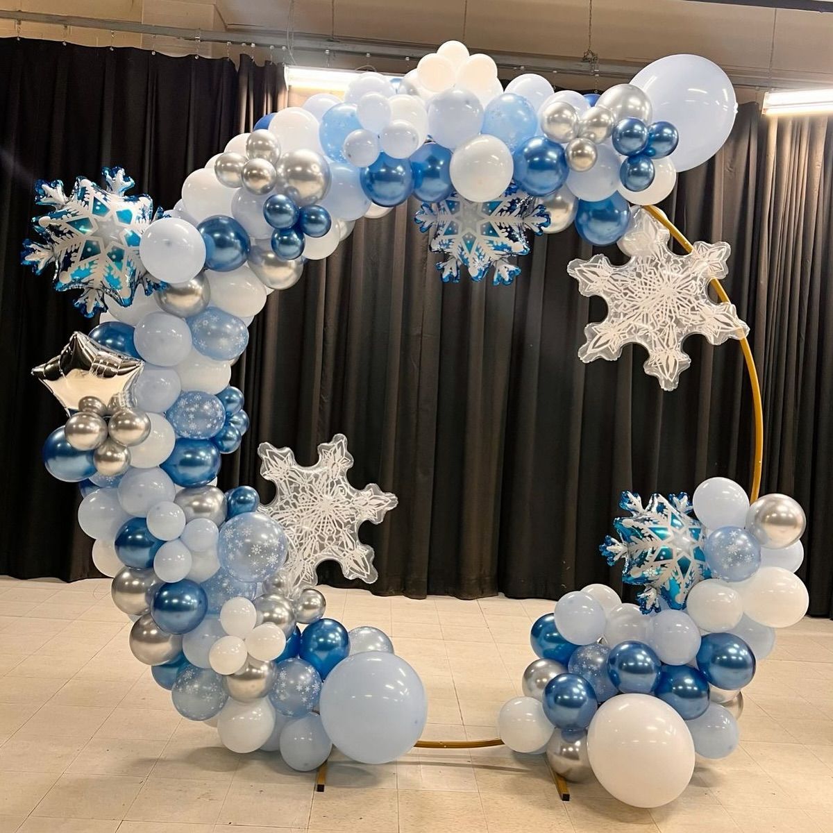 Balloon arch: blue, white, and silver balloons in a circular shape, with snowflake and star decorations.
