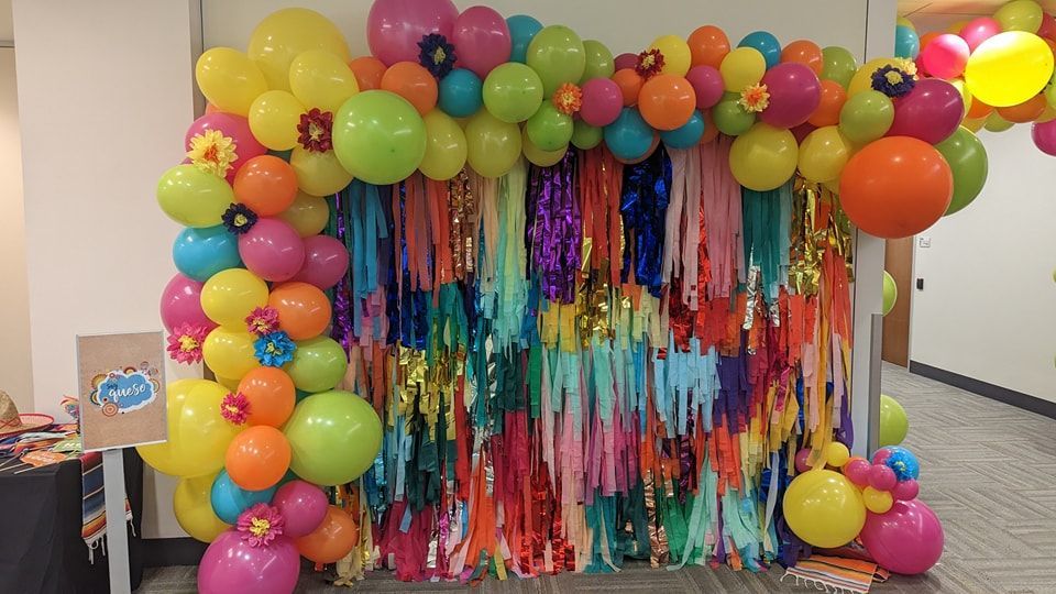 Colorful balloon arch and fringe backdrop for a party.