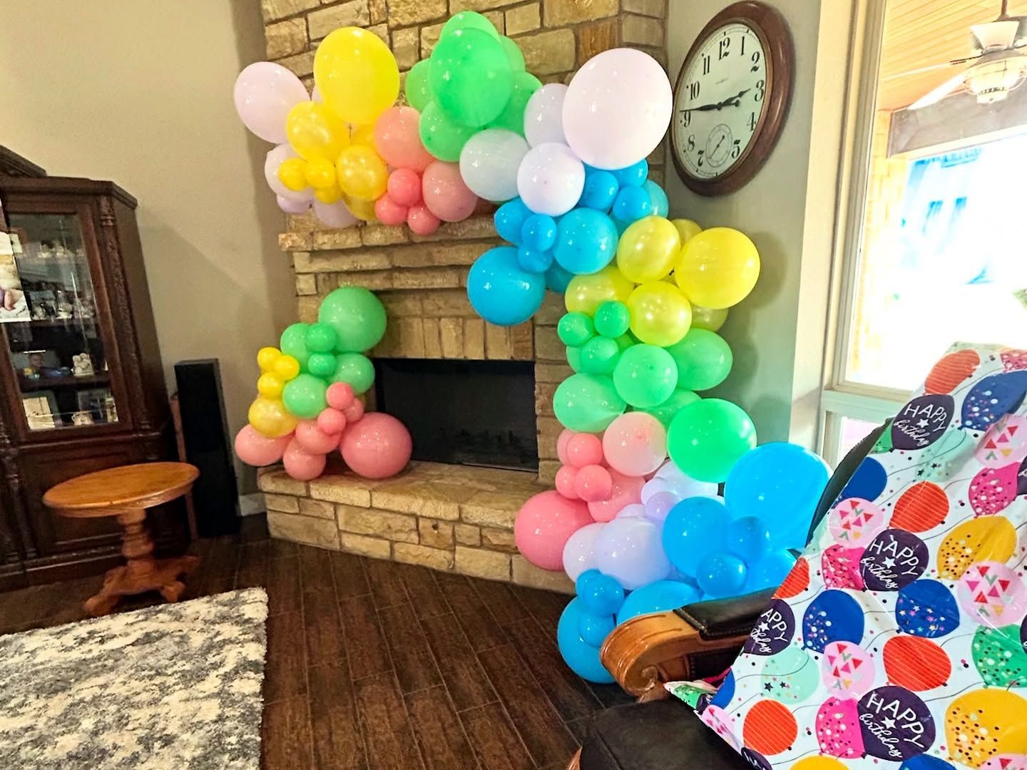 A colorful balloon arch decorates a fireplace.