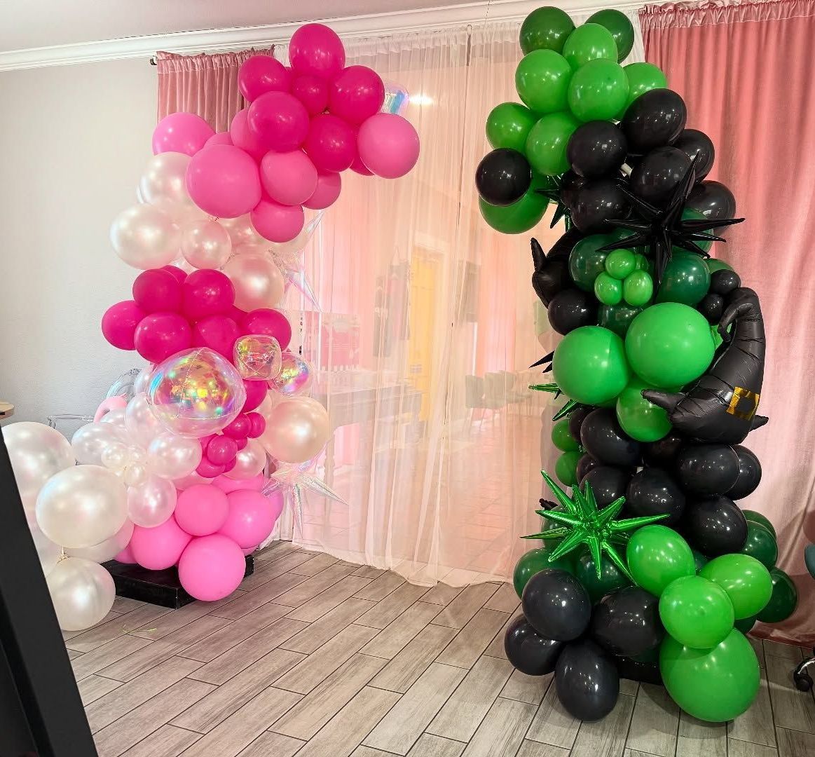 Two balloon arches: one pink/white, one black/green, indoors.