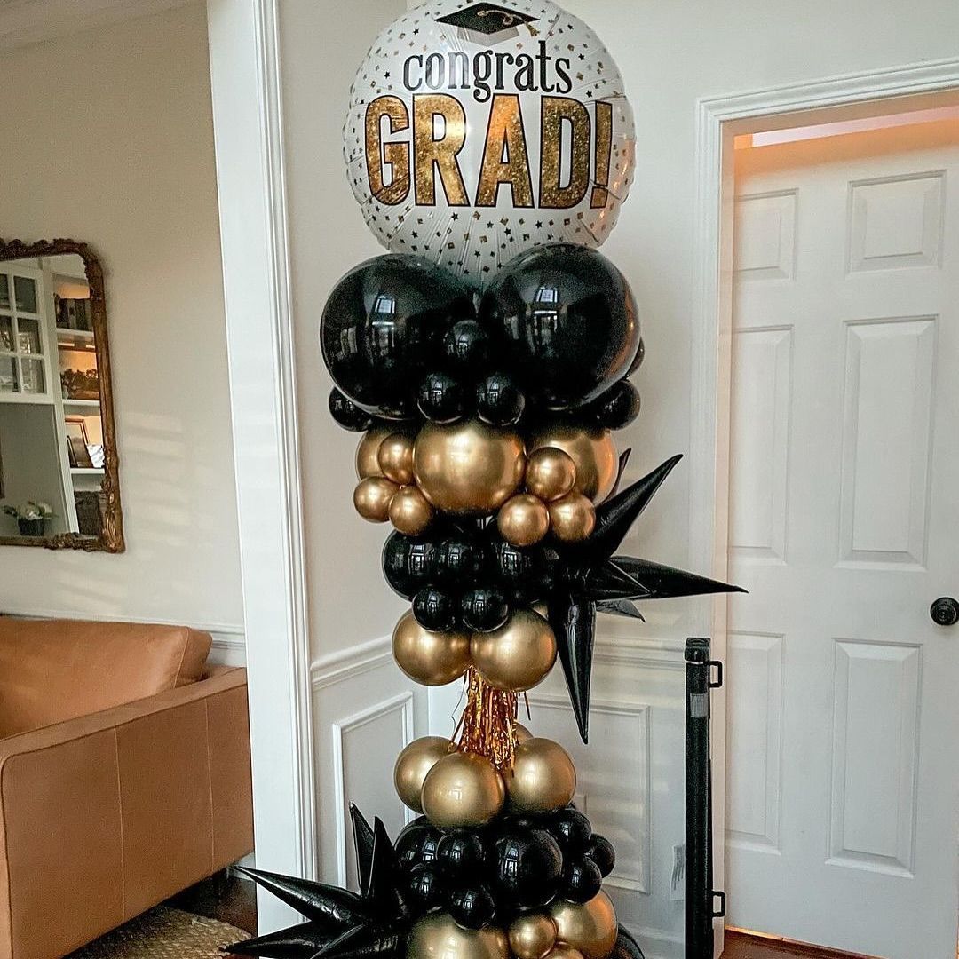 Graduation balloon display with black, gold balloons, and a