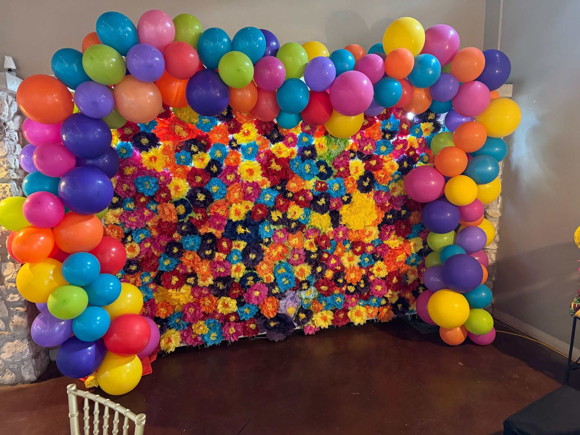 Colorful balloon archway frames a floral wall backdrop, ready for a photo.