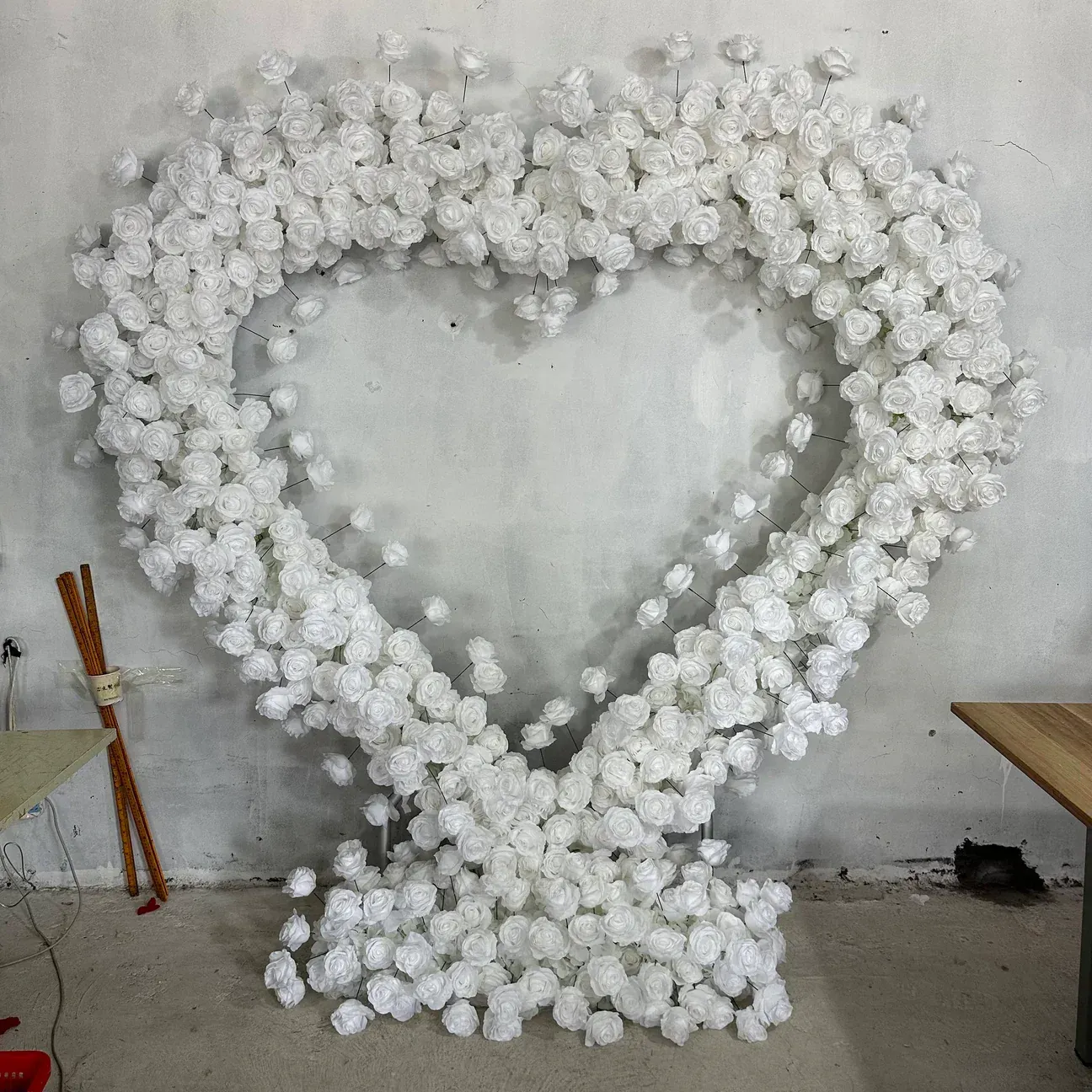 White flower heart arch against a gray wall.