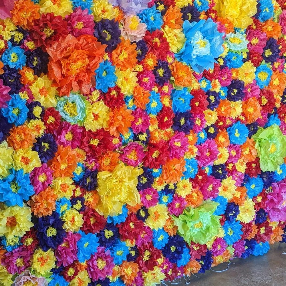 Colorful wall covered in bright paper flowers of various colors.