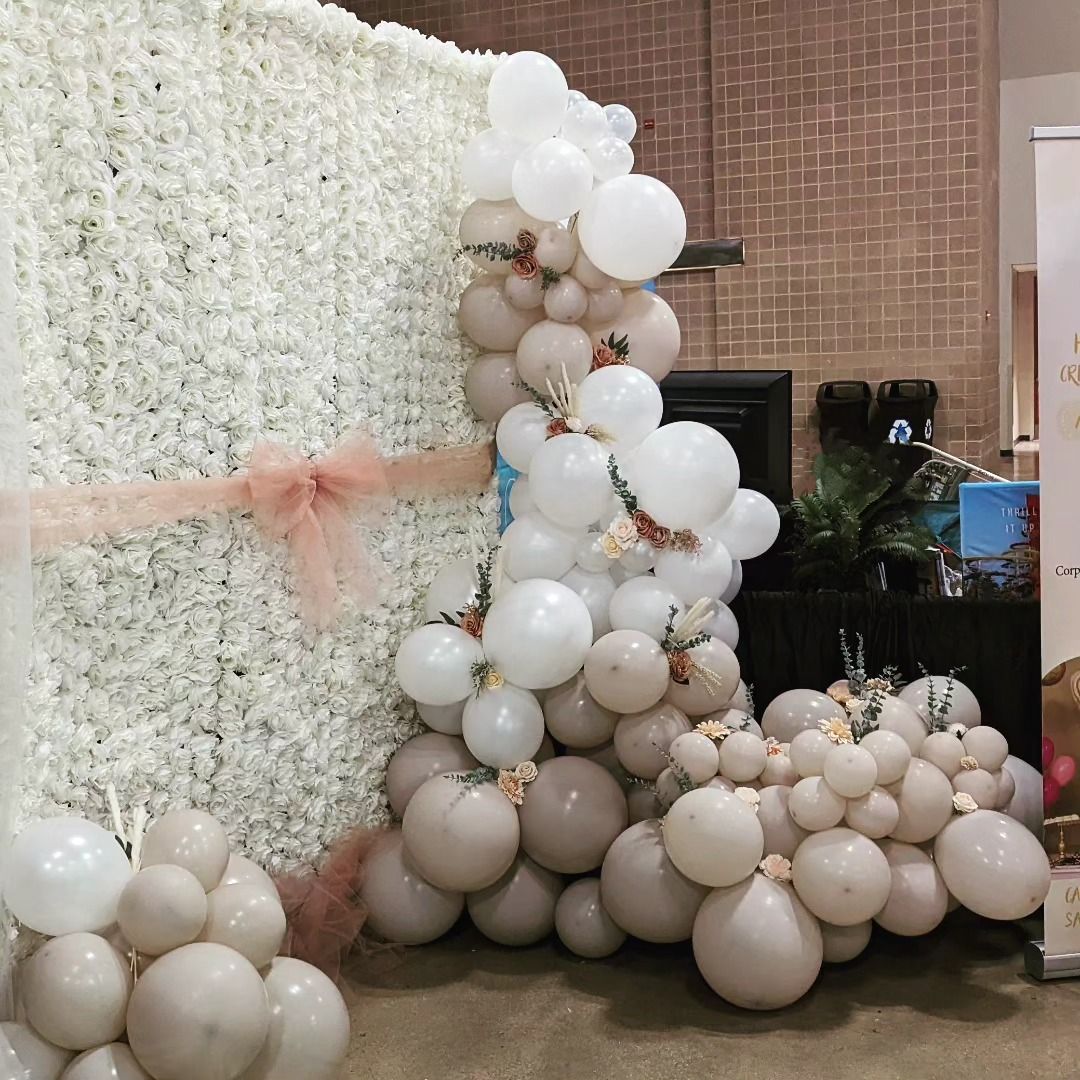 White flower wall with balloon arch of beige, white, and blush balloons.