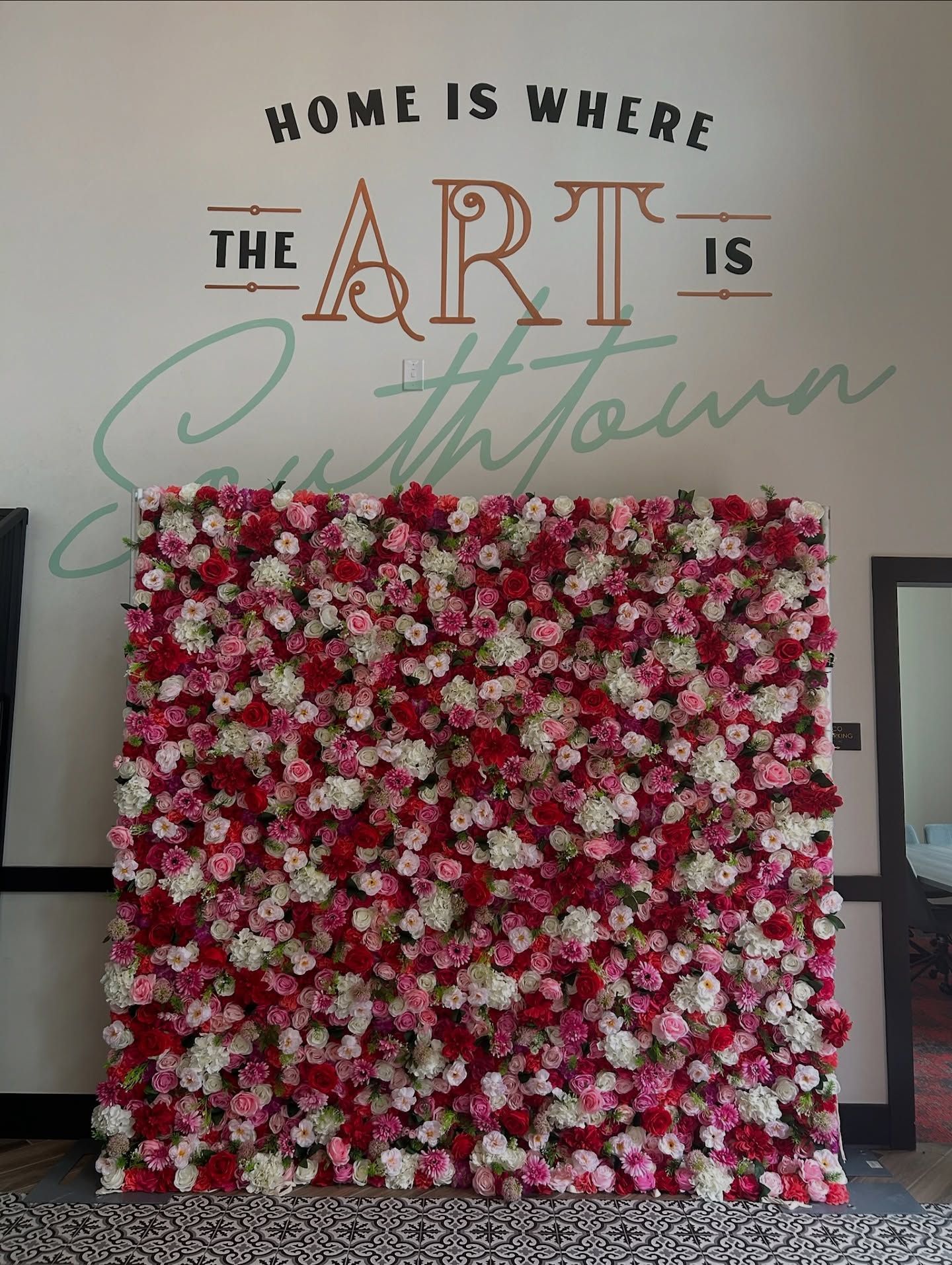 Flower wall with red, pink, and white blooms, below text reading