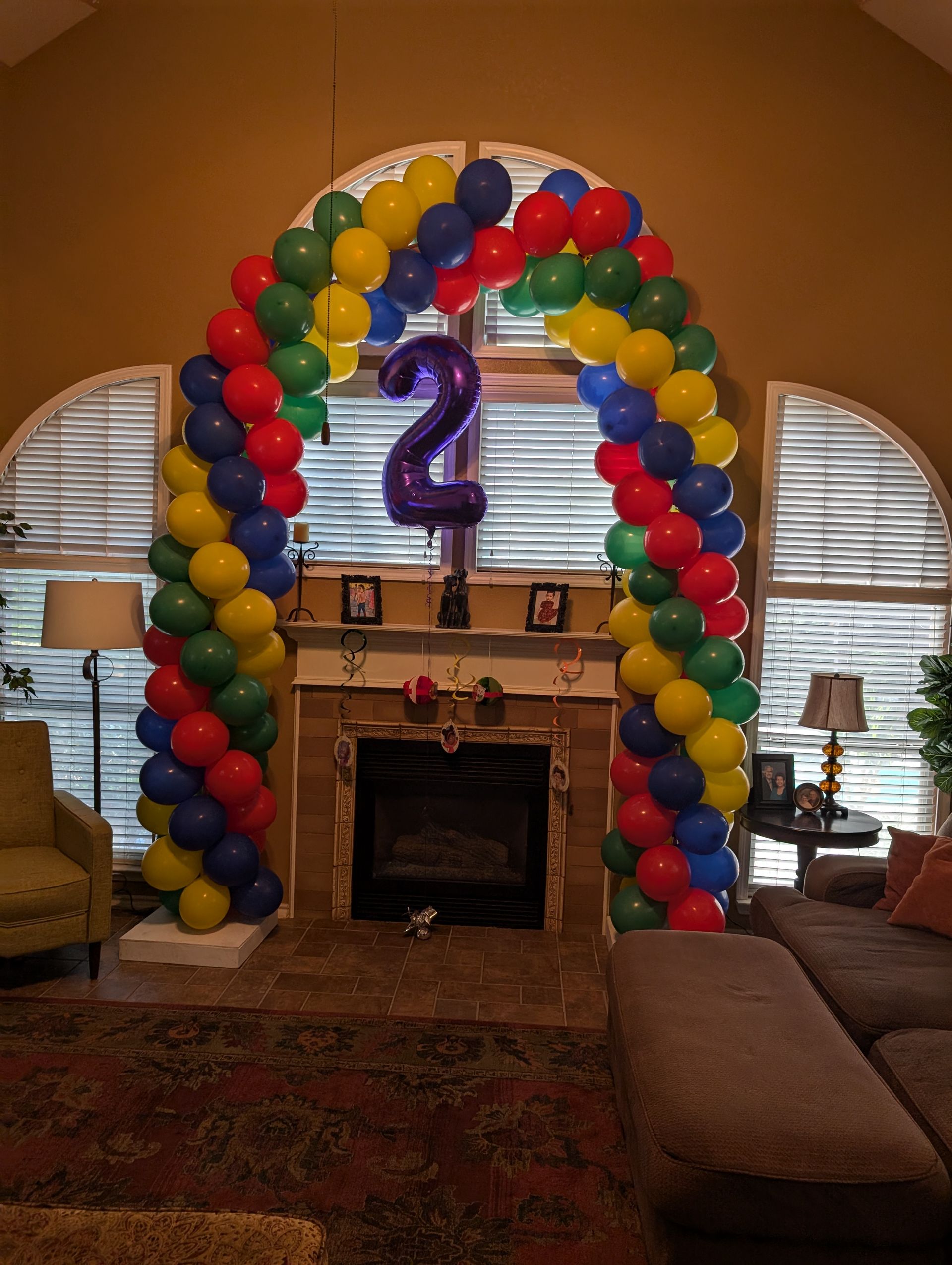 Colorful balloon archway around a fireplace, with a