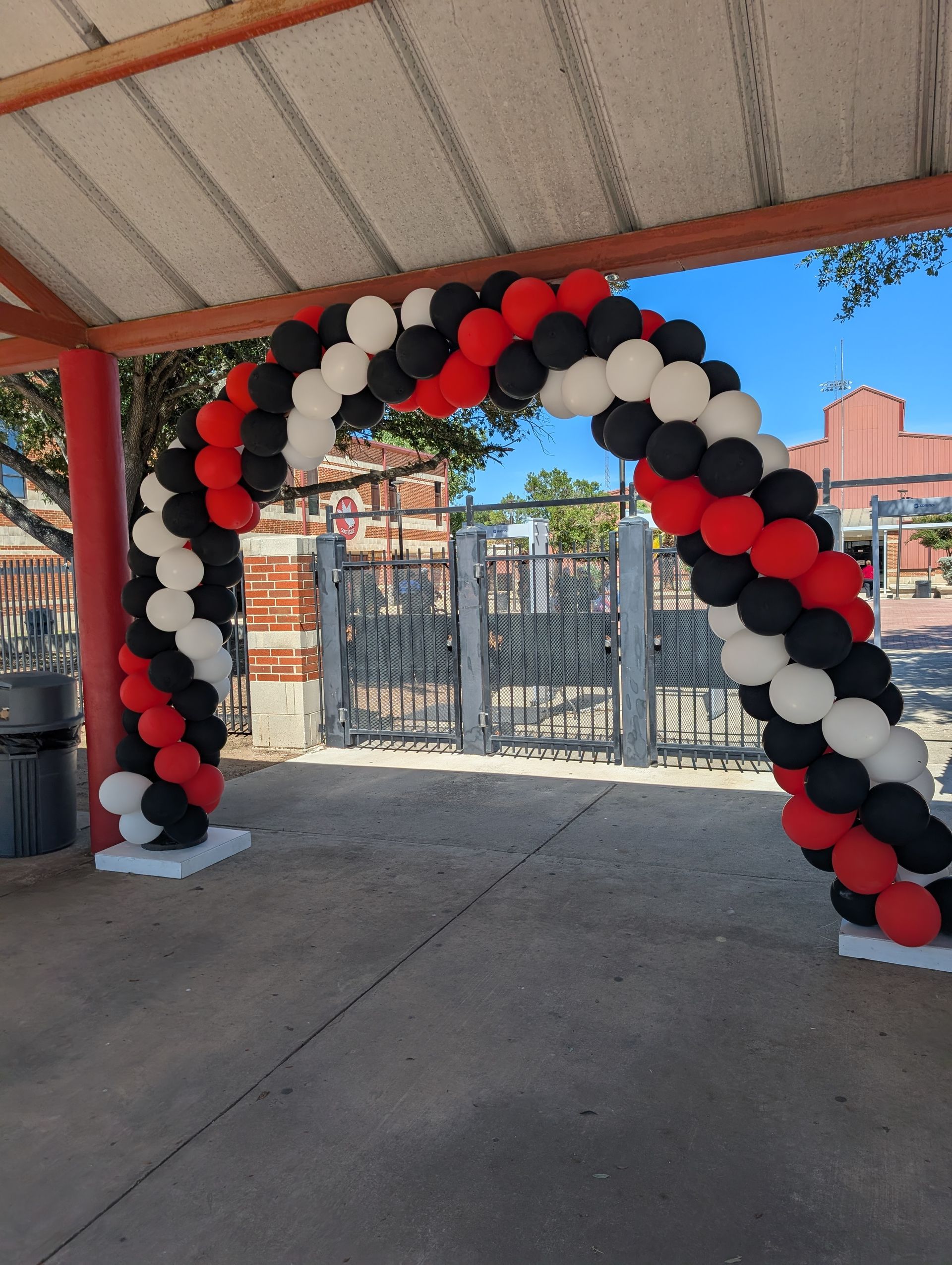 Balloon archway in red, black, and white at an outdoor event.