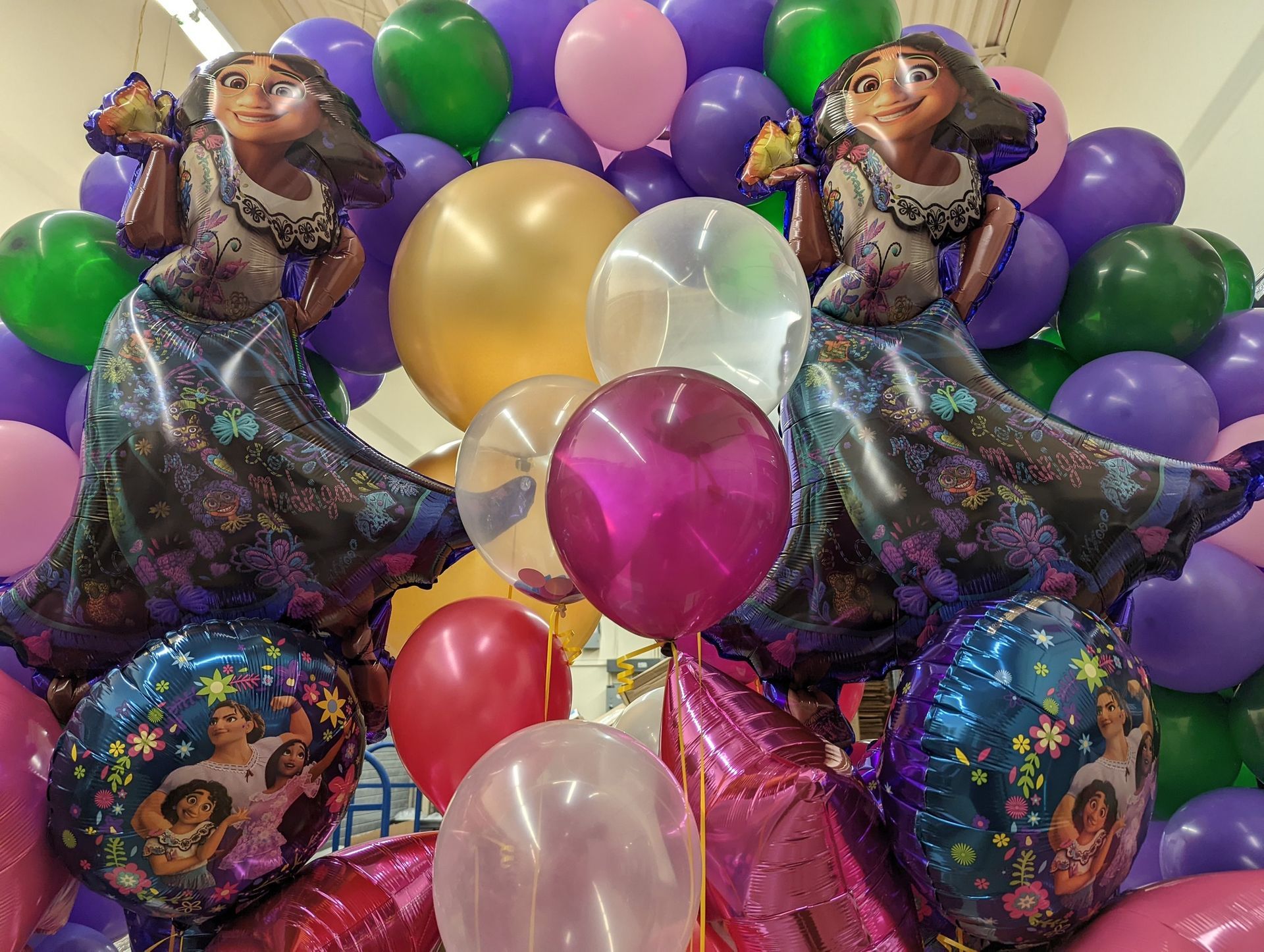 Balloons with Encanto character inflatables, purple, gold, and pink.