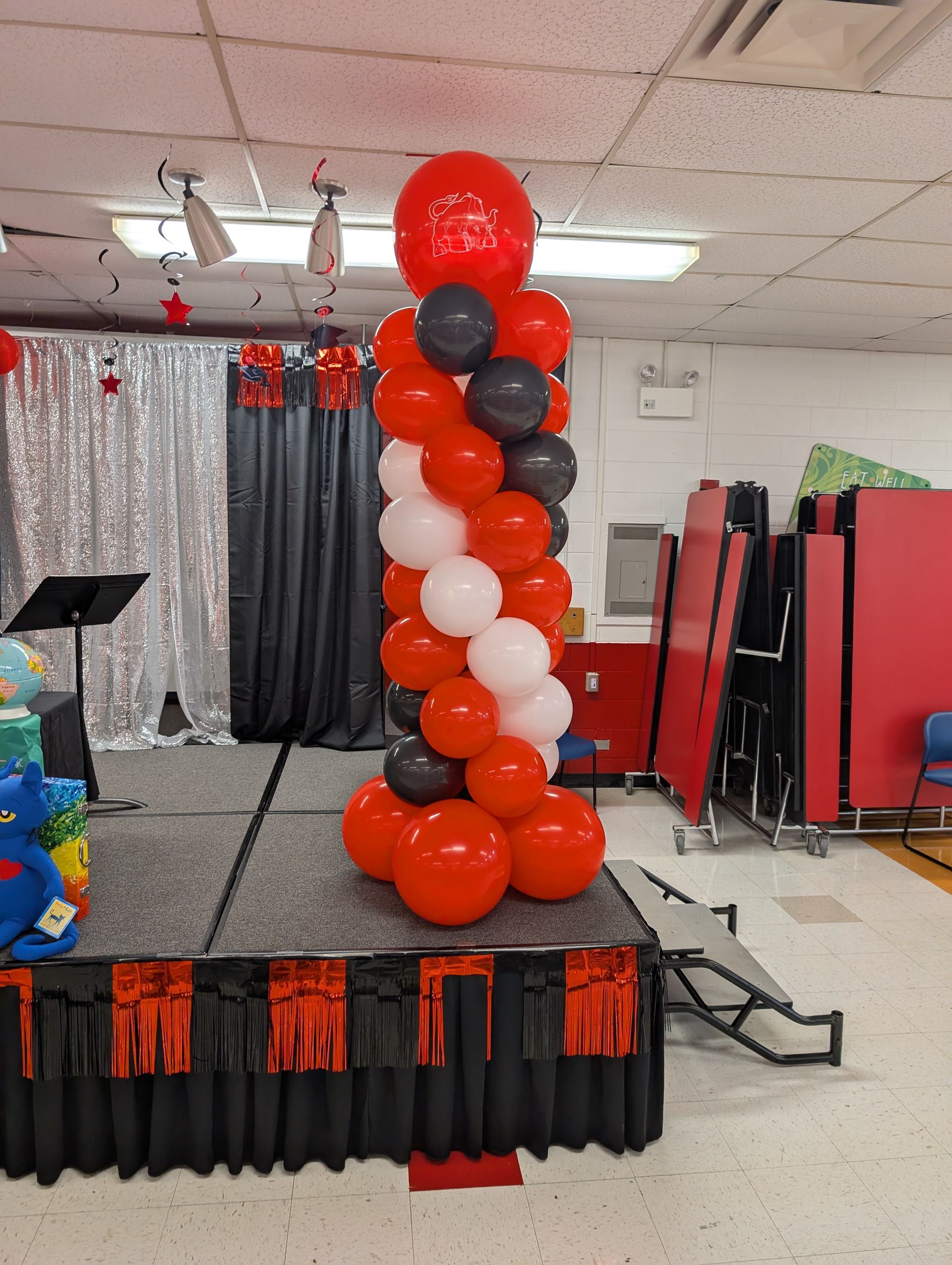Red, white, and black balloon column on a stage; party decorations.