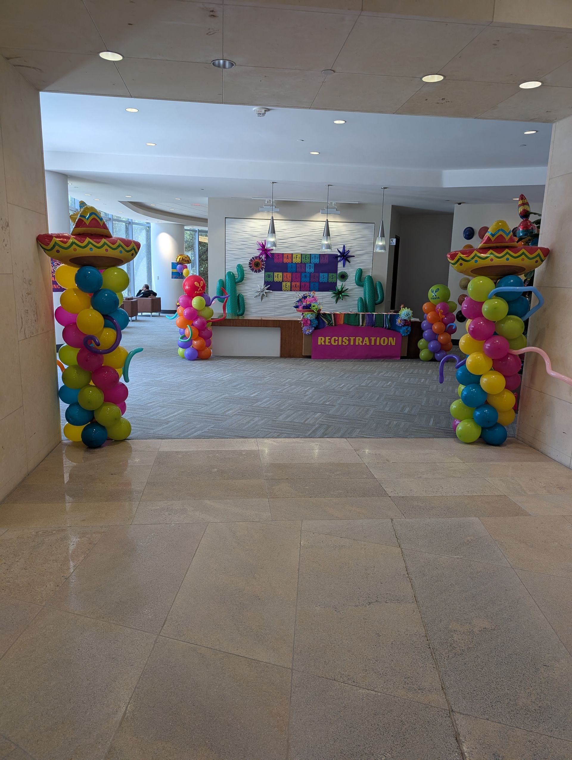 Entrance decorated with colorful balloons and sombreros for a party.