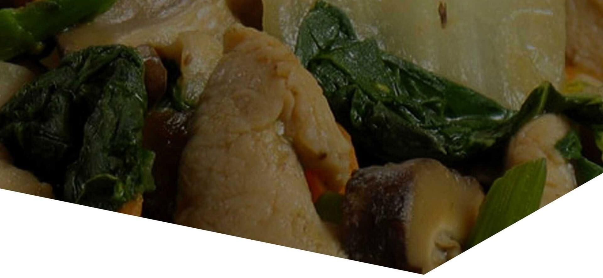 Un primer plano de un plato de comida con espinacas y champiñones.