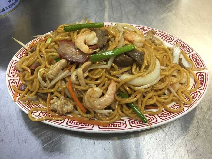 Un plato de fideos con carne y verduras sobre una mesa.