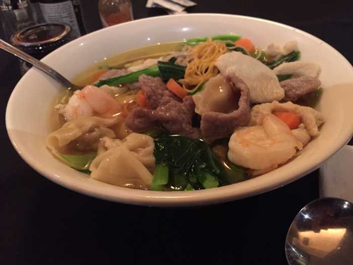 Un tazón de sopa con carne y verduras con una cuchara dentro.