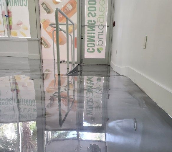 Modern glass entrance with a clean, grey polished epoxy floor finish.