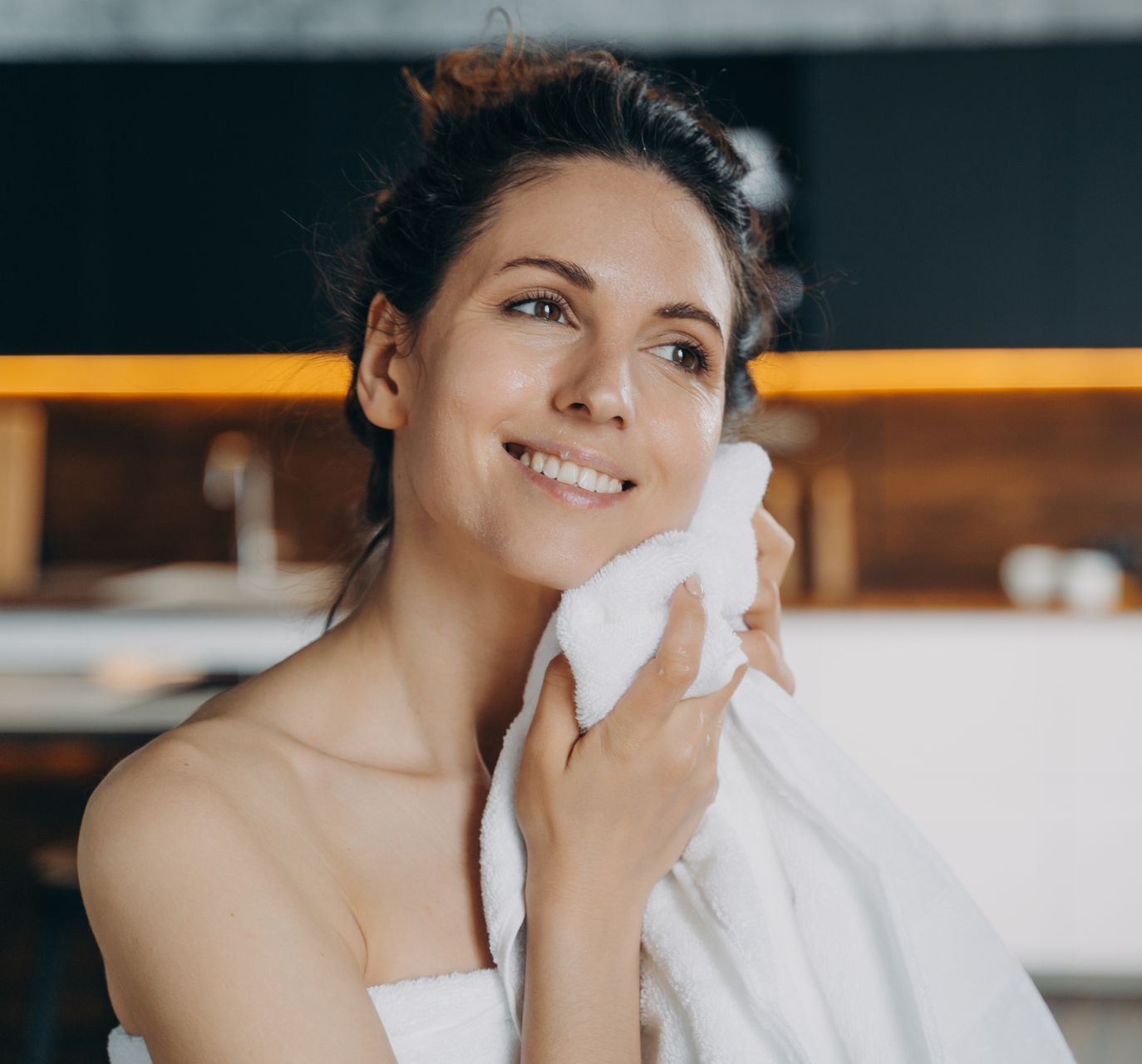 a woman wipes her face with a white towel