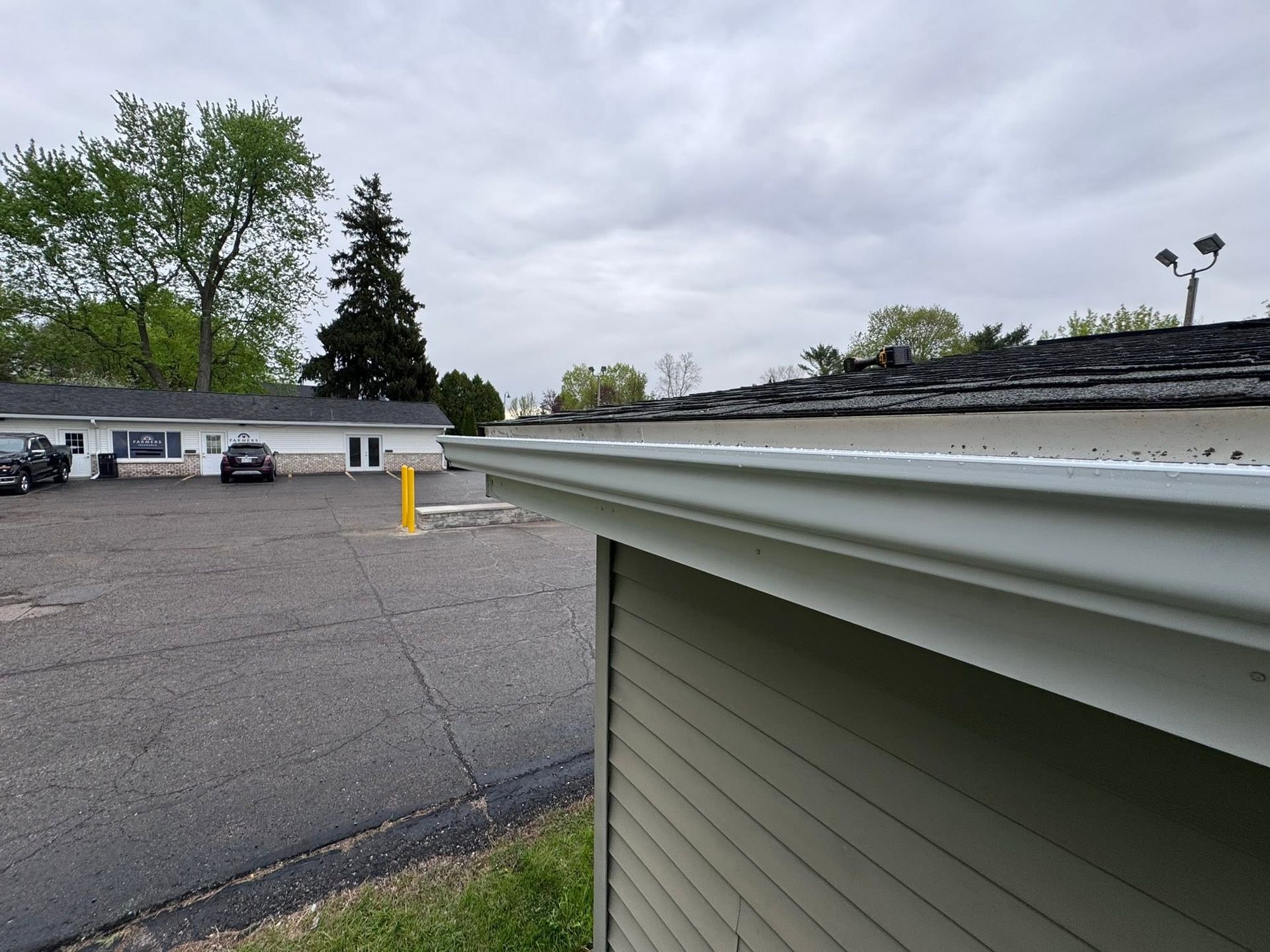 Parking lot beside a building with a white gutter and cloudy sky overhead
