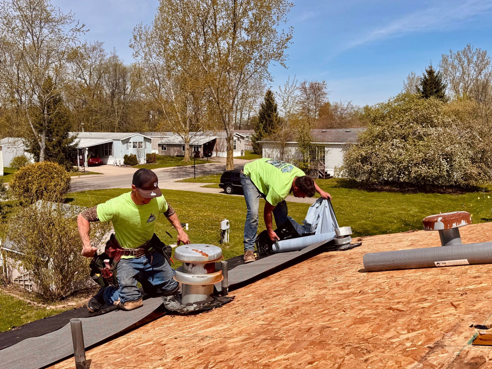 Workers installing roofing felt on a house roof on a sunny day