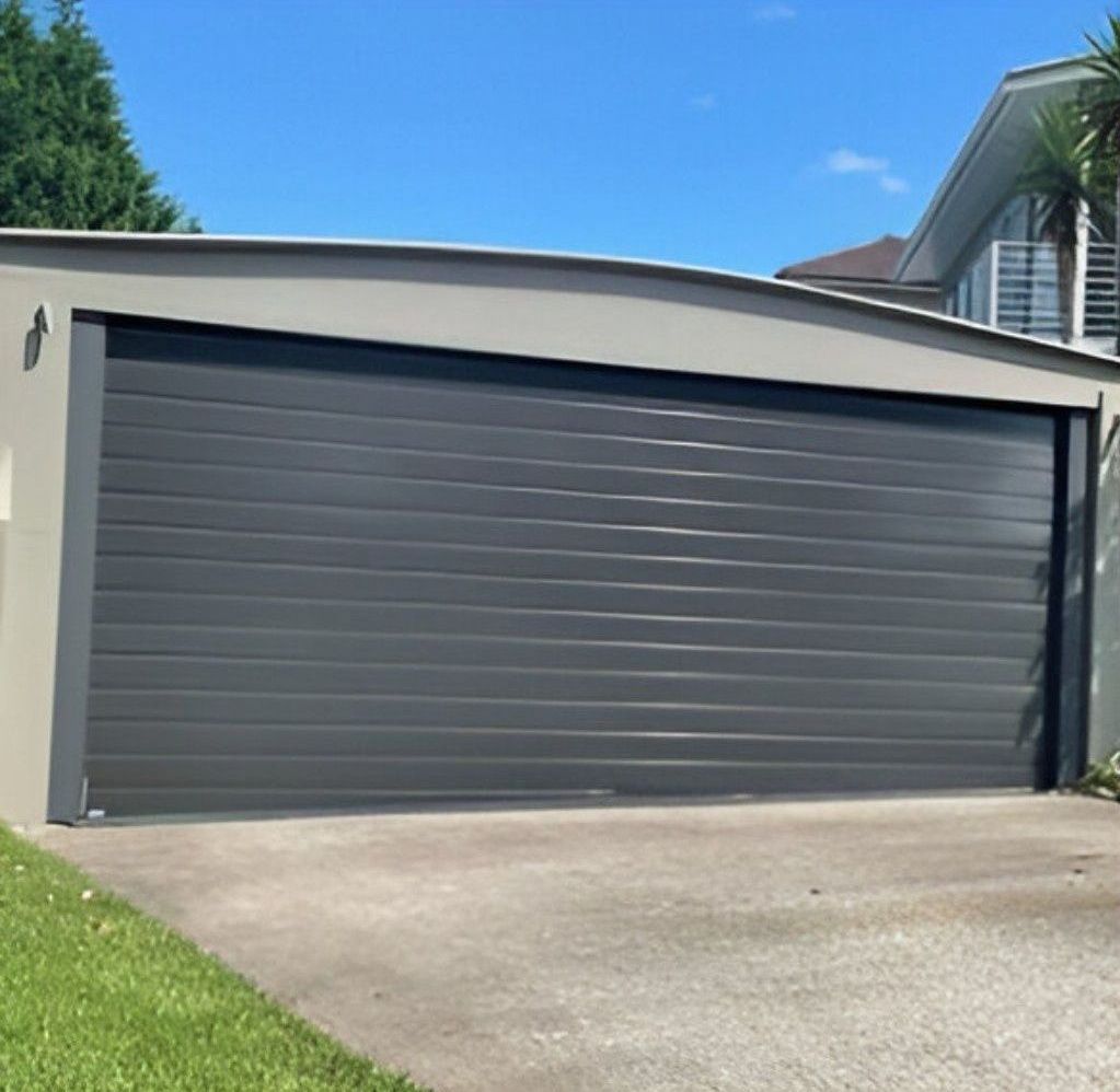 A Large Black Garage Door Is Open in Front of A House — Gem Garage Doors in Coffs Harbour, NSW