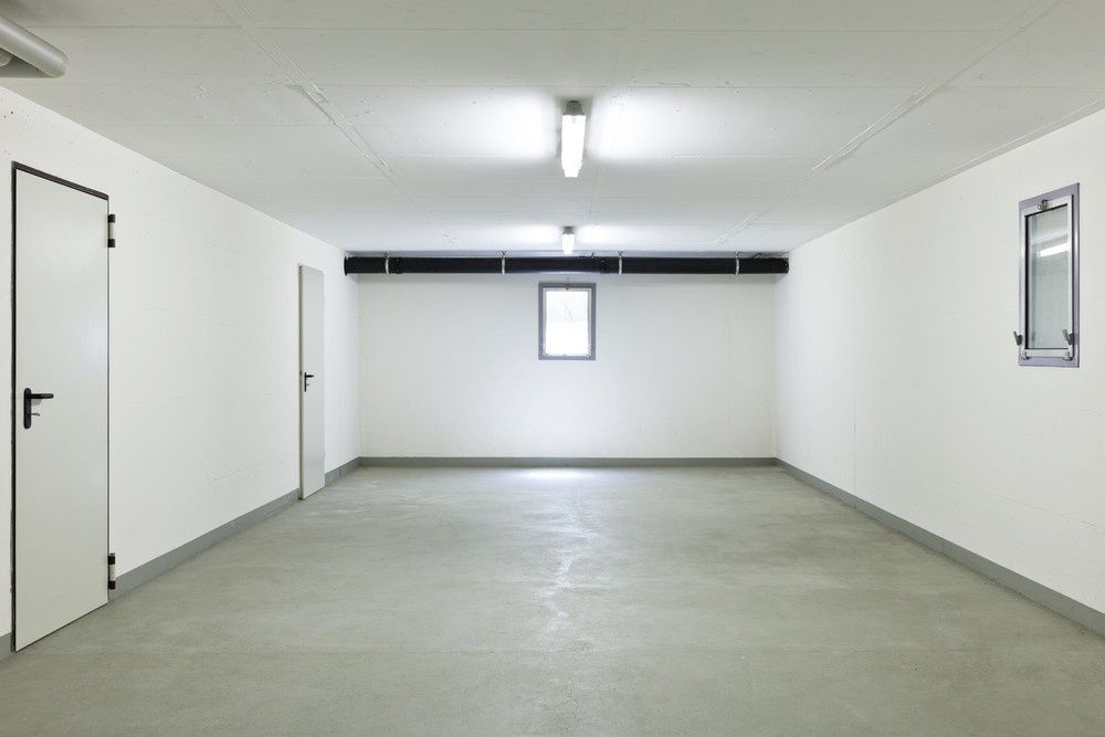 An Empty Garage with White Walls and A Concrete Floor — Gem Garage Doors in Coffs Harbour, NSW