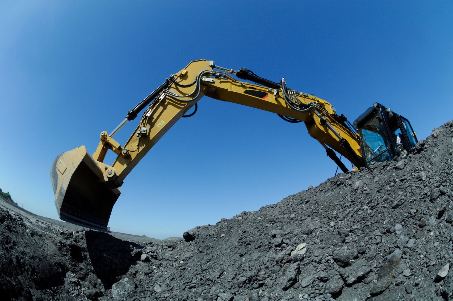 a yellow excavator is digging in a pile of rocks