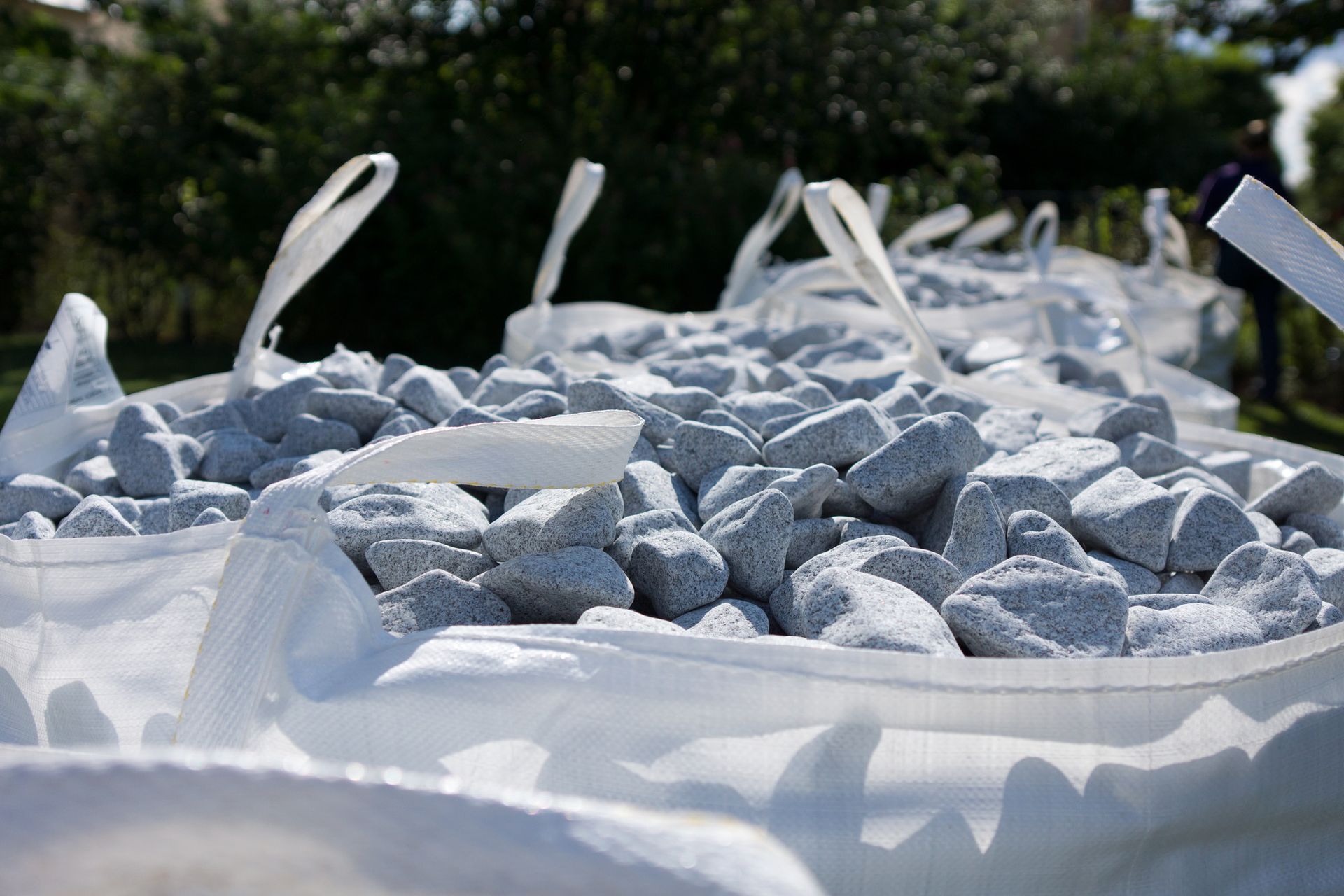 a pile of white bags filled with rocks is sitting on the ground