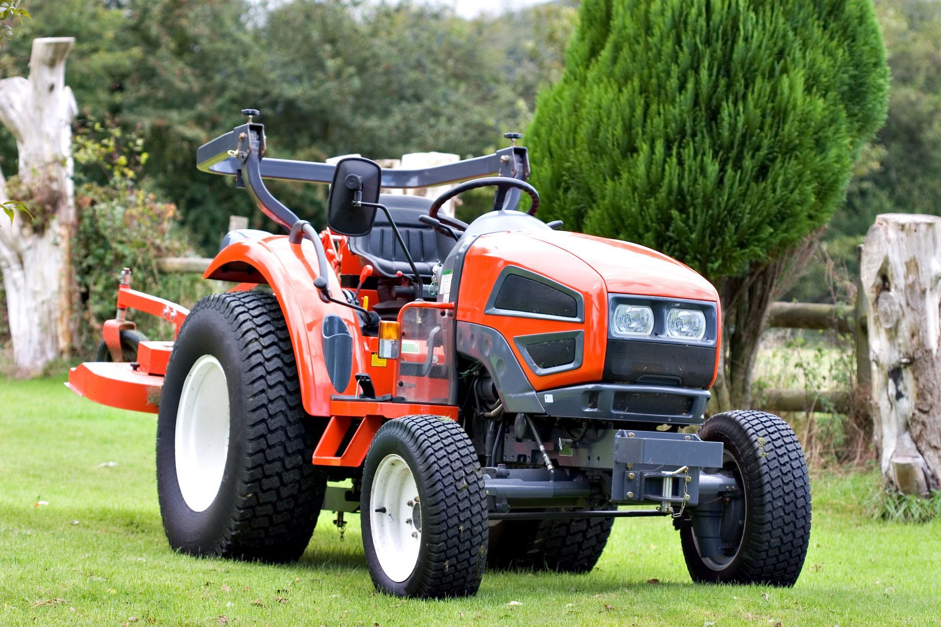 a small orange tractor is parked in a grassy field