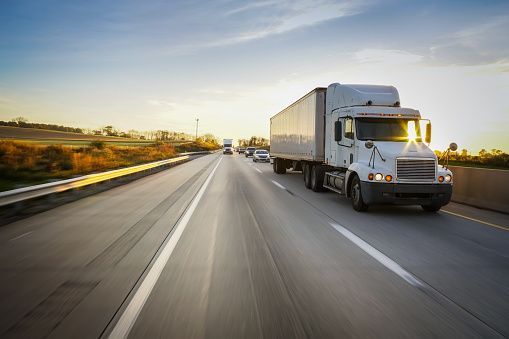 18-wheeler tractor trailer truck on the highway with blur and sunburst
