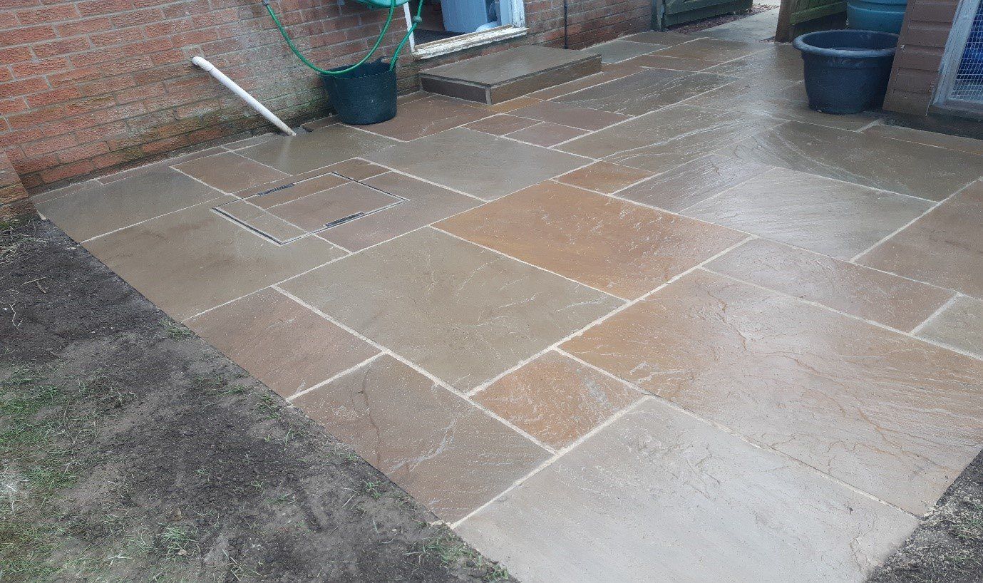 Indian sandstone patio with new step and recessed manhole cover