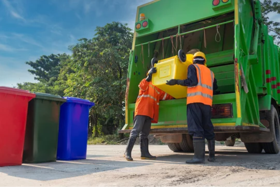 Garbage collectors working in unison to empty trash bins into a waste removal truck, efficiently managing waste disposal.