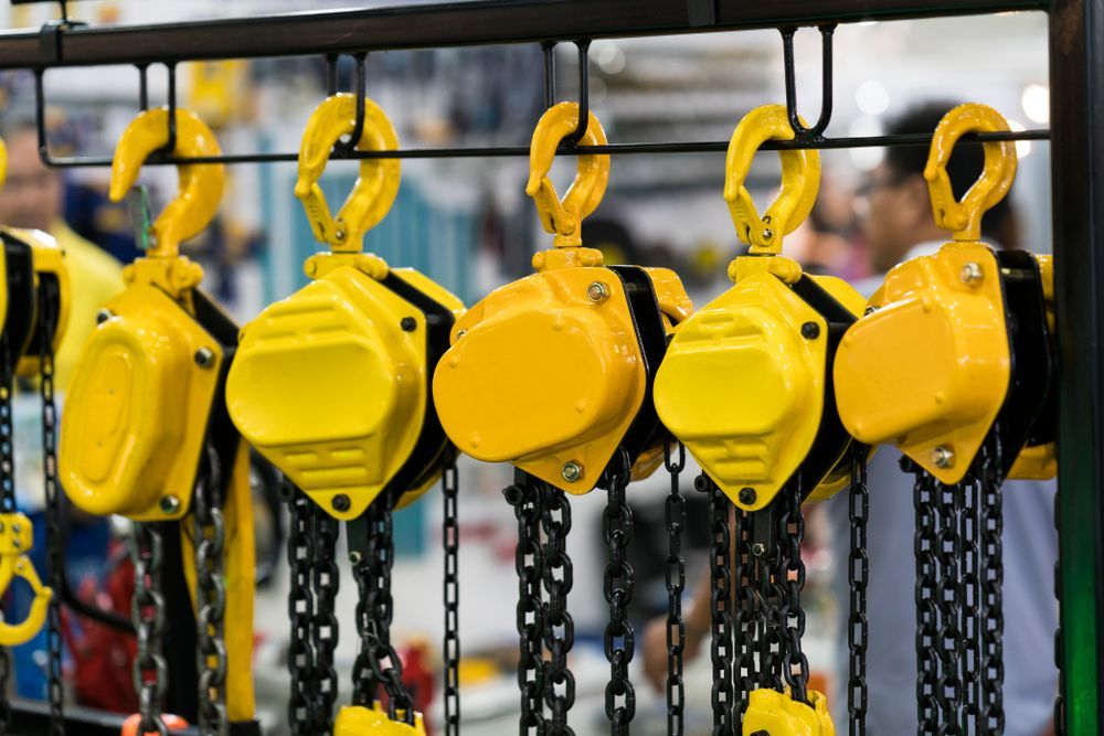 A Bunch of Yellow Chain Hoists Hanging on A Rack — Border Bolts & Fasteners in Tweed Heads South, NSW