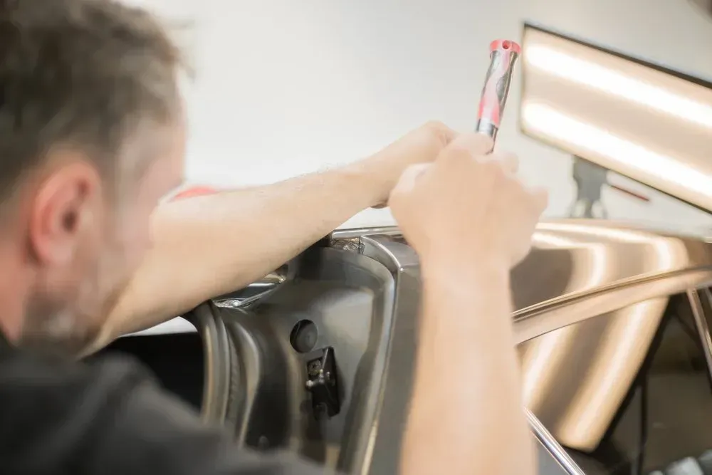 Man Using a Tool to Repair a Dent on a Car in a Repair Shop — Coastal Collision Repairs in Buderim, QLD