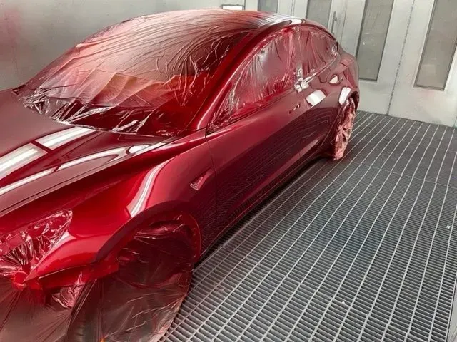 Red Car in a Paint Booth, Covered in Plastic, Mid-painting Process — Coastal Collision Repairs in Buderim, QLD