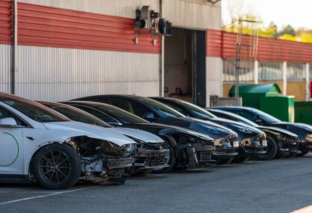 Line of Damaged Tesla Cars Parked Outside a Red-trimmed Building — Coastal Collision Repairs in Buderim, QLD