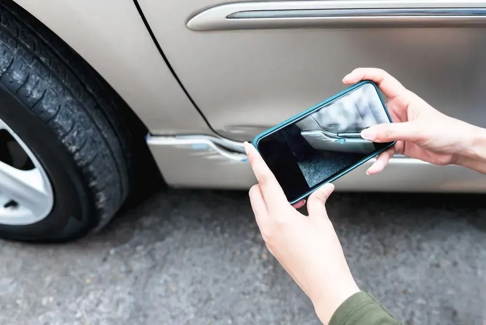 Person Using a Smartphone to Photograph a Dented Car Door — Coastal Collision Repairs in Buderim, QLD