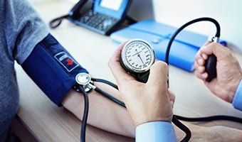 Physicals — Doctor Measuring Blood Pressure in Wilmington, NC