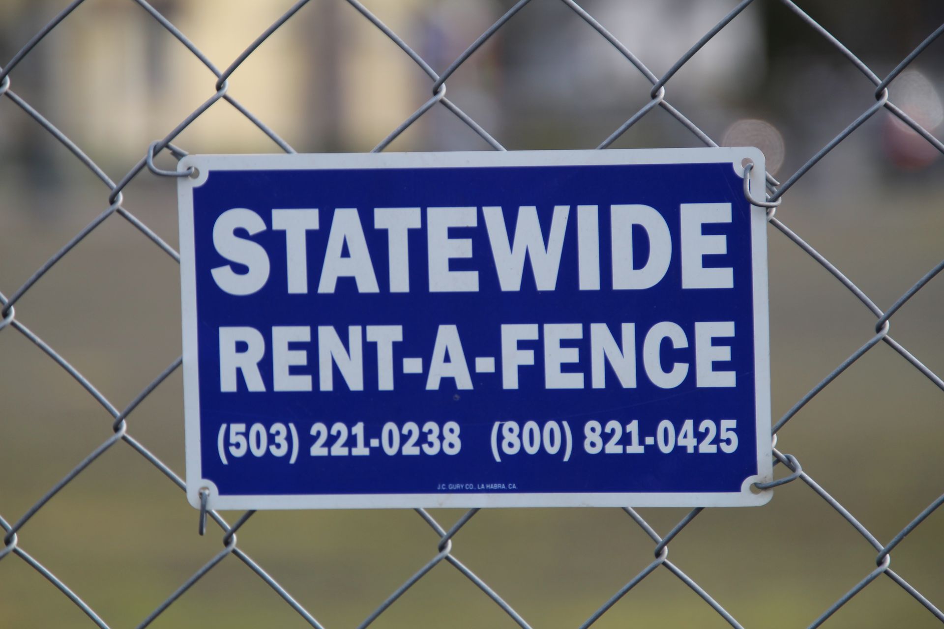 Chain-link gate in an industrial alley with a small warning sign and concrete walls.