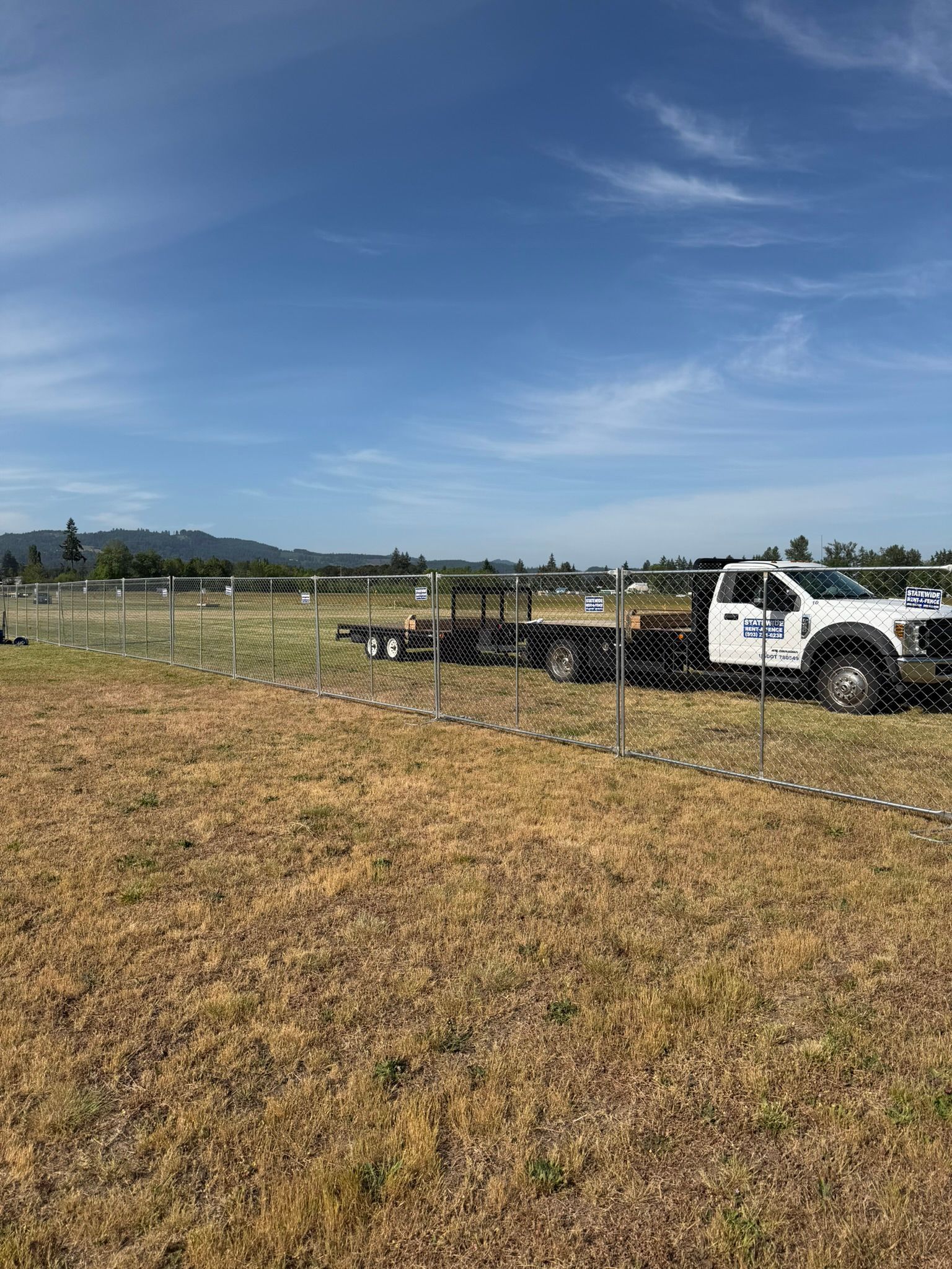 White pickup truck beside fenced field under a clear blue sky